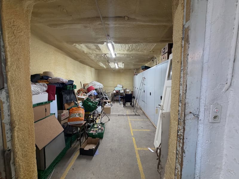 a corridor with lots of boxes, wheelchair, lamps on the ceiling, storage lockers
