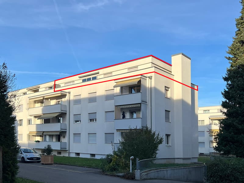 Multistory apartment building with red outline, balconies, parked car