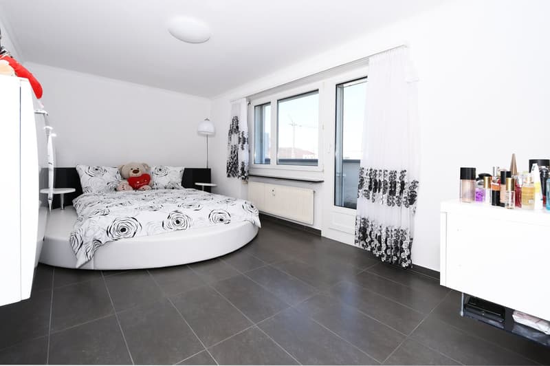 white circular bed, white flooring, white walls, white bedside tables, grey floor