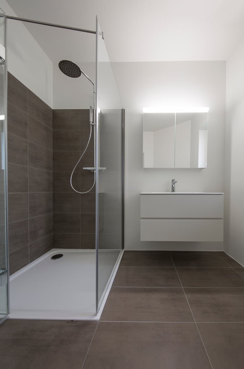 modern bathroom with walk-in shower, white tiles, mirror, sink, and faucet