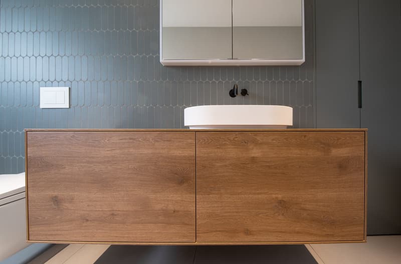 modern bathroom with blue tiles, wooden cabinet, white sink, mirror