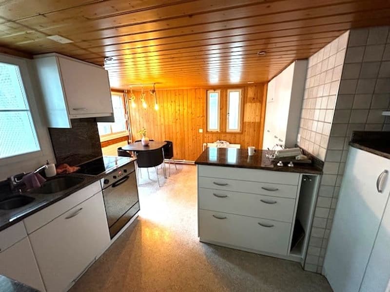 kitchen with white cabinets, black countertops, wooden ceiling, gas stove, oven, sink, dining table, chairs, windows
