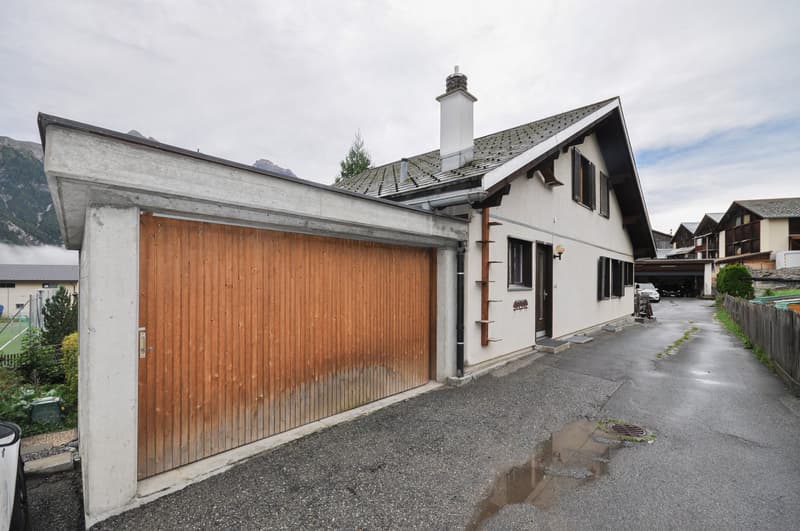 white house, wooden garage, white roof, white pipe on wall, mountains in the background