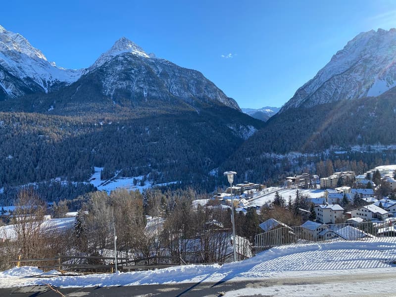 Snow-covered ground, town houses, mountains, street lights, road