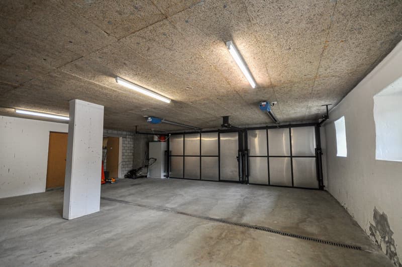 Large open garage space with concrete floor, exposed ceiling, and storage units along the walls.