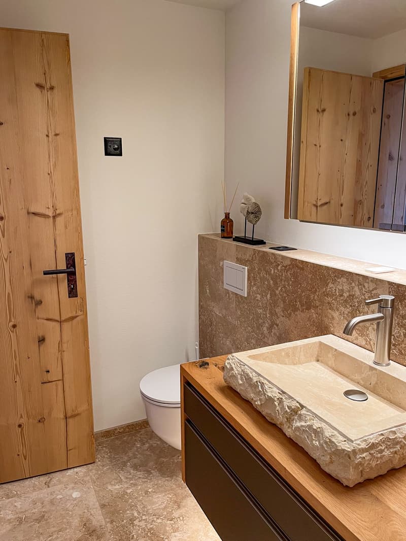 bathroom, wooden door, marble countertop, stone sink, wooden floor, mirror, white toilet, silver faucet