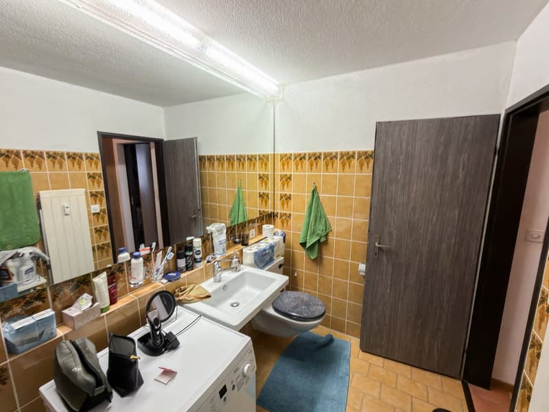 tiled walls, white sink, mirror, towel rack, washing machine