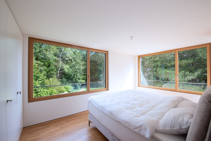 wooden floor, white walls, large windows with balcony, bed with white duvet and pillows