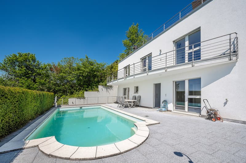 Modern white house with swimming pool, balcony, and outdoor seating area