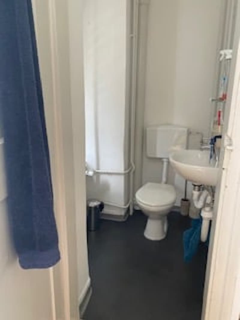 white toilet, white sink, blue towel, small trash can