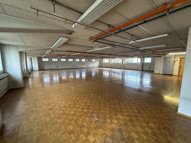 spacious room with hardwood floors, exposed beams, numerous windows, ventilation systems, white walls, and radiators