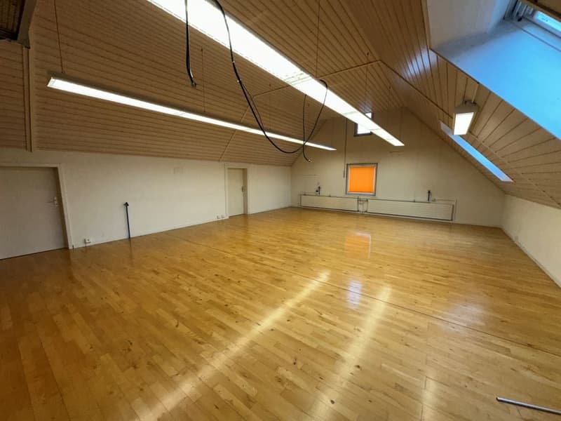 large room, wooden floor, 4 windows, 2 doors, fluorescent ceiling lights