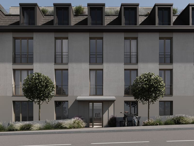 Modern apartment building, gray exterior, large windows, balconies, entrance with awning, bicycles parked outside