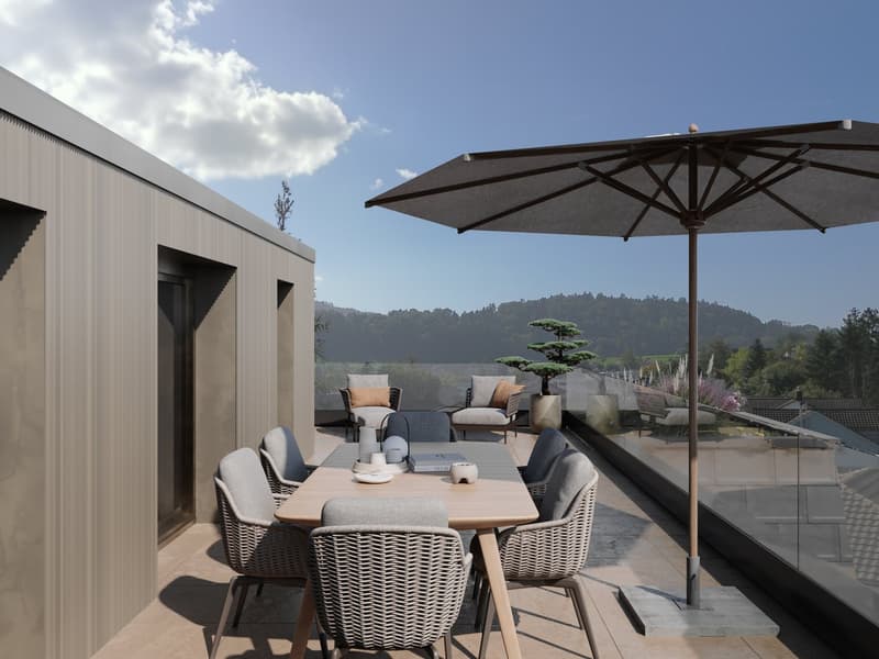 Outdoor dining area with a table, chairs, and an umbrella, surrounded by a glass railing, with a view of the mountains.