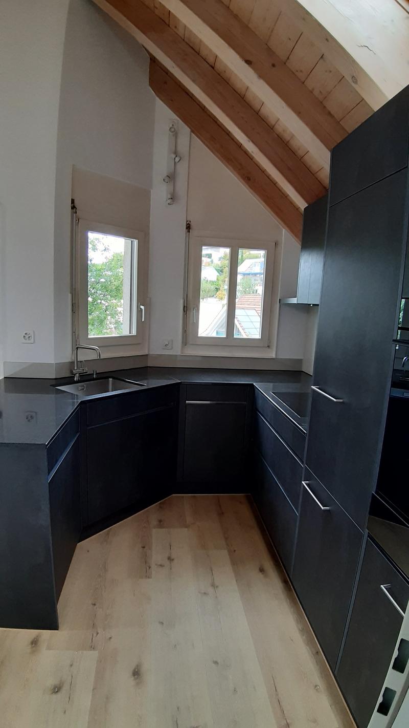 modern kitchen with black cabinets, wooden floor, stainless steel sink, two windows, wooden ceiling