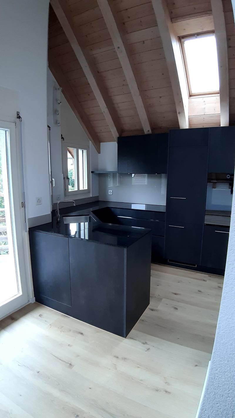 modern kitchen with black countertops, black cabinets, wooden ceiling, glass door, windows