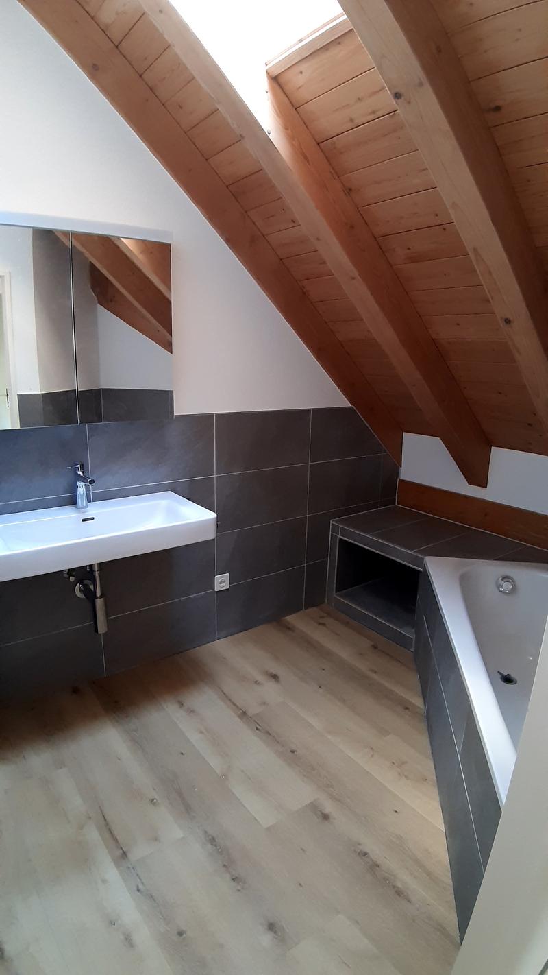 Bathroom with wooden floor, gray tiles, white sink, mirror, bathtub, wooden ceiling