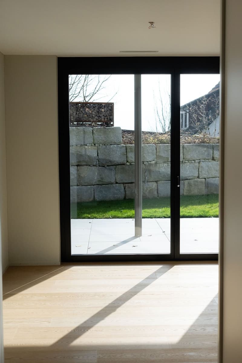glass sliding doors, wooden floor, white walls, large stone wall outside