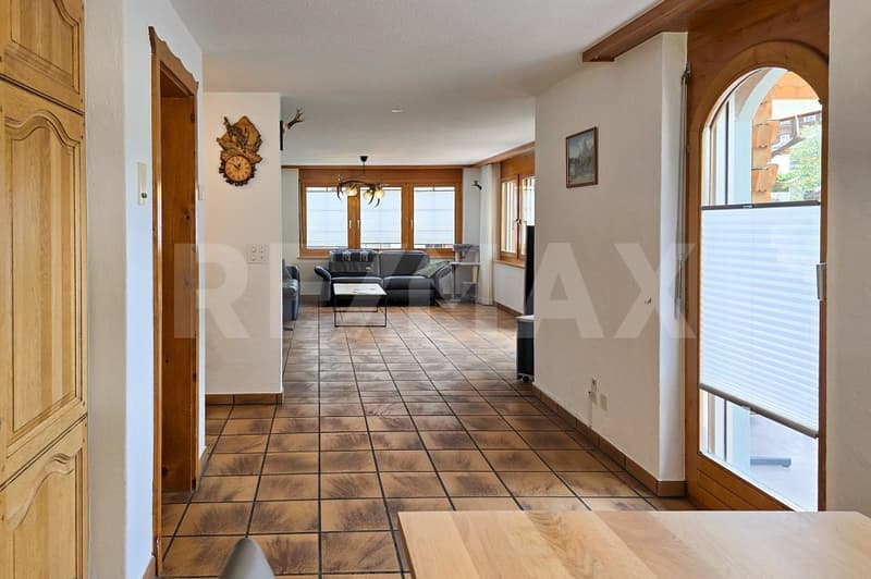 tiled floor, wooden doors, living room with couch, coffee table, chandelier, windows with blinds, picture frame, wooden table