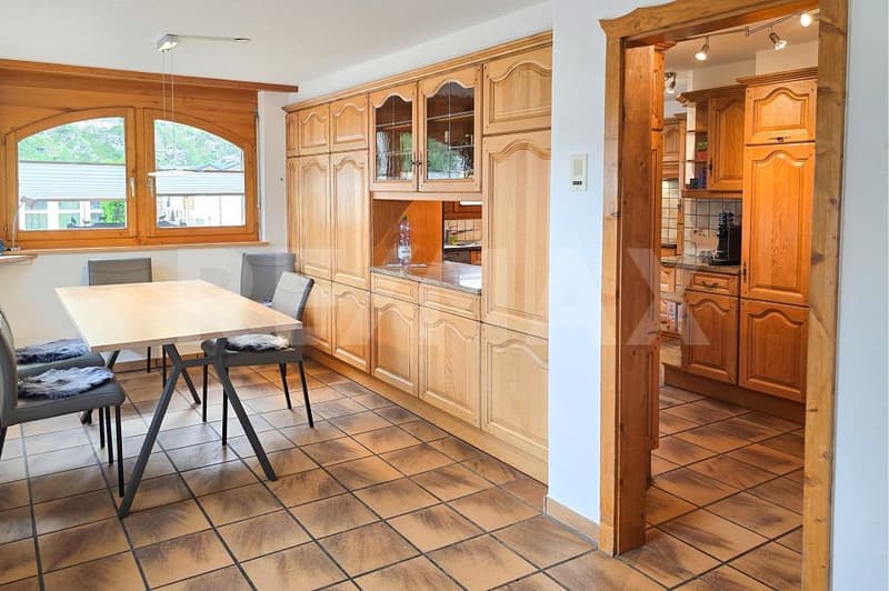 Dining room with wooden table and chairs, wooden cabinets, tiled floor, large windows