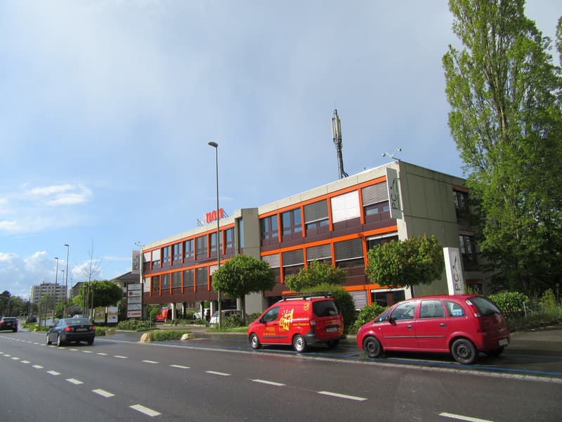 Office building with several windows, orange and gray color scheme, two story, in the corner of the street, street lights, cars parked in front