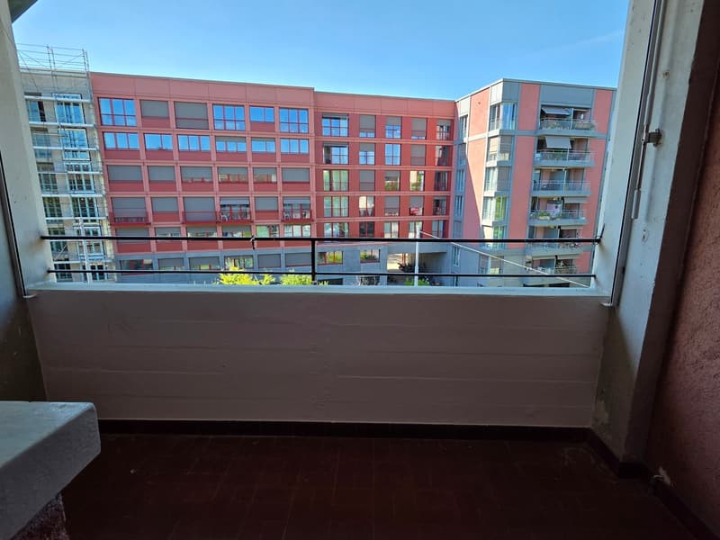 Balcony with a view of the building, white walls, wooden floor, black railings