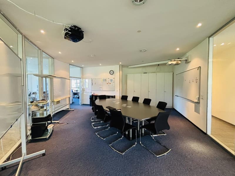 large oval table, chairs, whiteboard, overhead projector, cabinets, carpeted floor