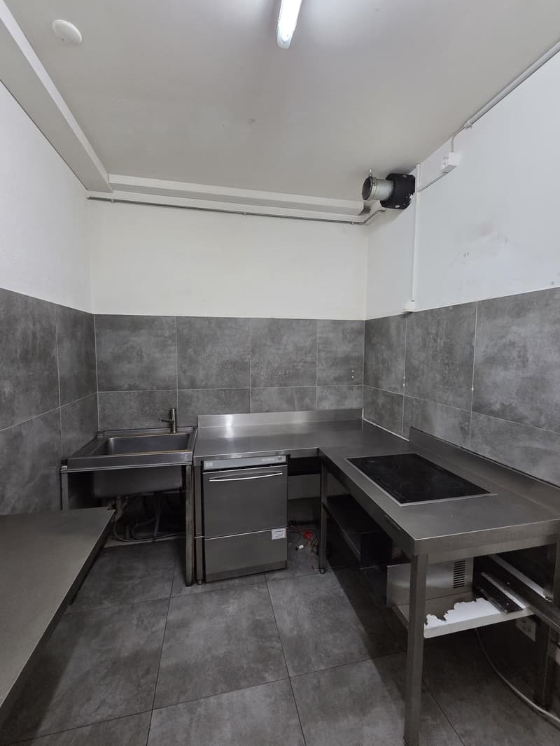 A small kitchen area with a sink, dishwasher, and stovetop.