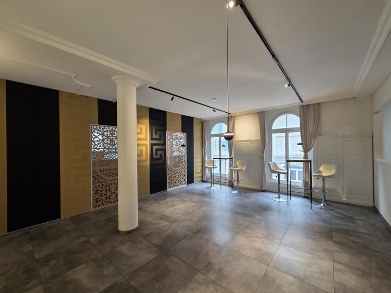 large open space, tiled floor, decorative wall panels, modern bar stools, track lighting