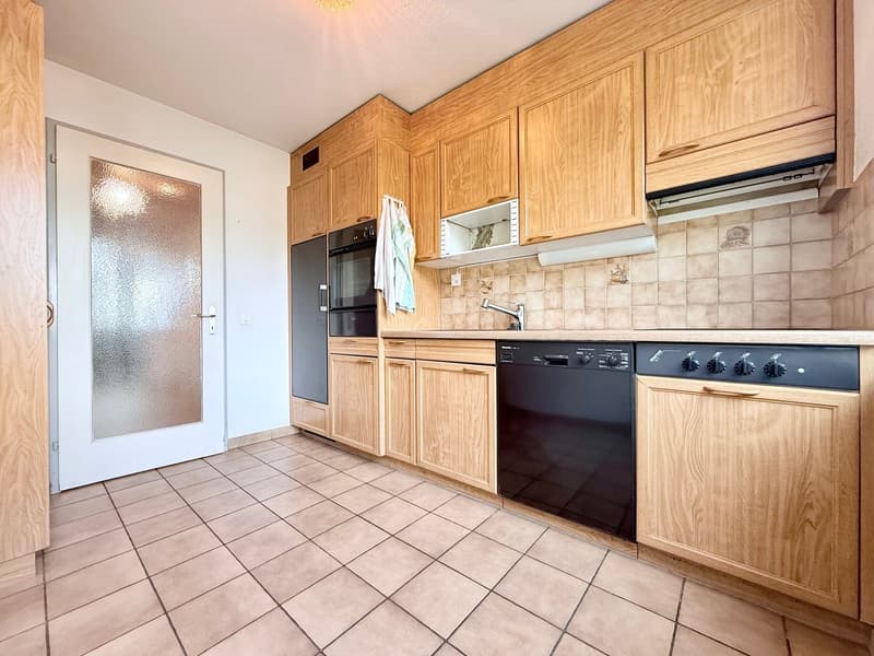modern kitchen with wooden cabinets, tiled floor, black appliances, dishwasher, oven, microwave, sink, faucet