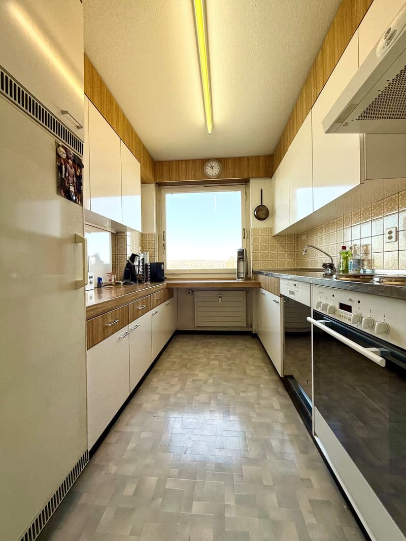 modern kitchen with white cabinets, wooden countertops, tiled floor, large window, appliances