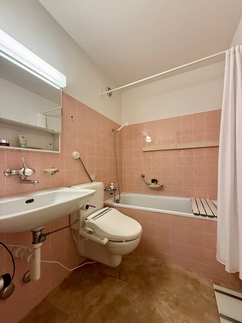Bathroom with pink tiles, white sink, toilet, bathtub, shower, mirror, and shower curtain