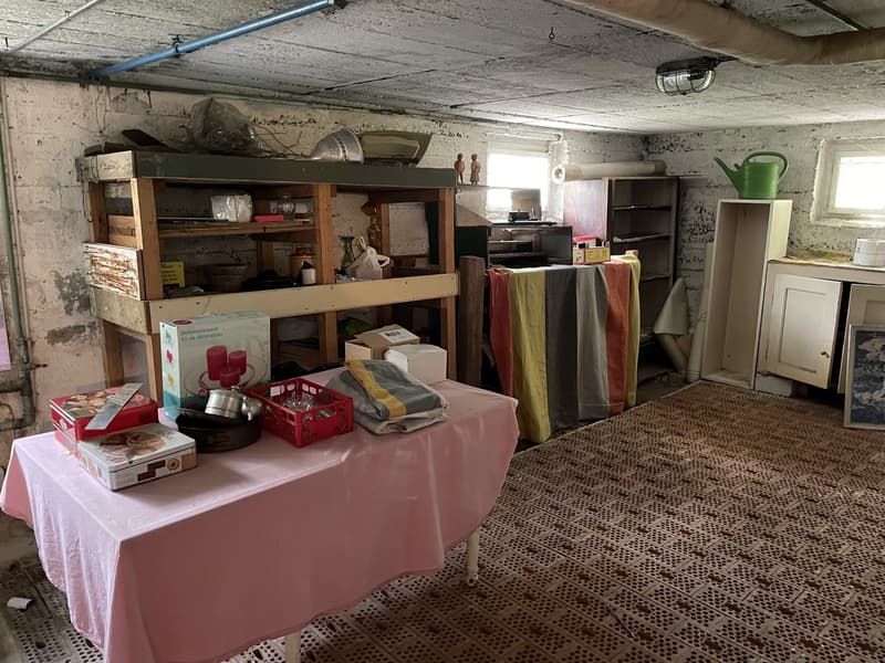 Basement room, various household items, storage shelves, a table, and a teapot.