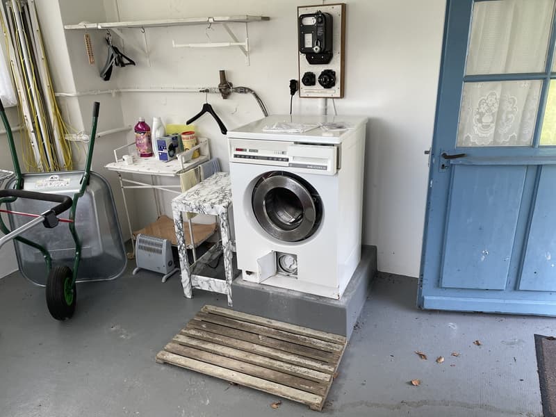 laundry room with washing machine, small table, folding table, small wooden shelf, meter on wall