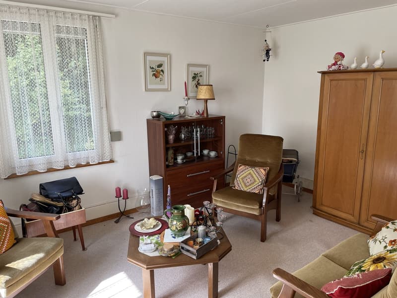 living room with a sofa, coffee table, lamp, window with curtain, chair, cabinet, side table, picture frames