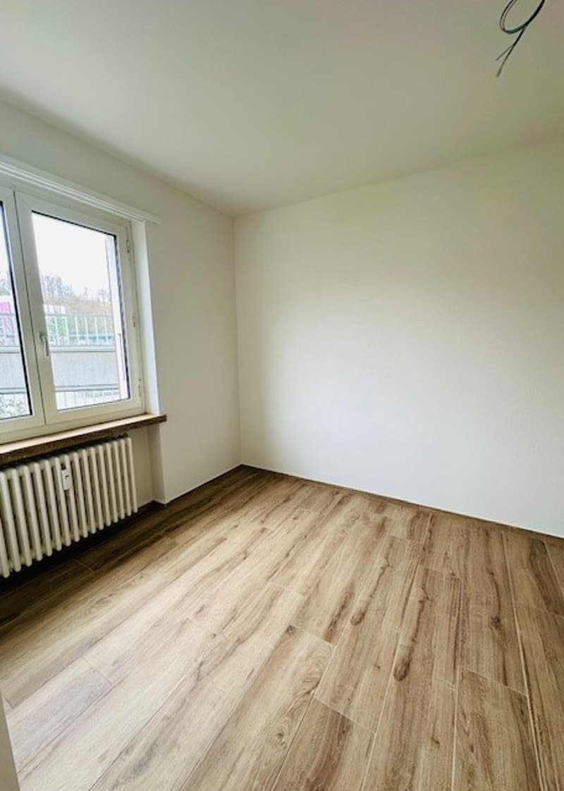 empty room, wooden floor, white walls, large window, white radiator