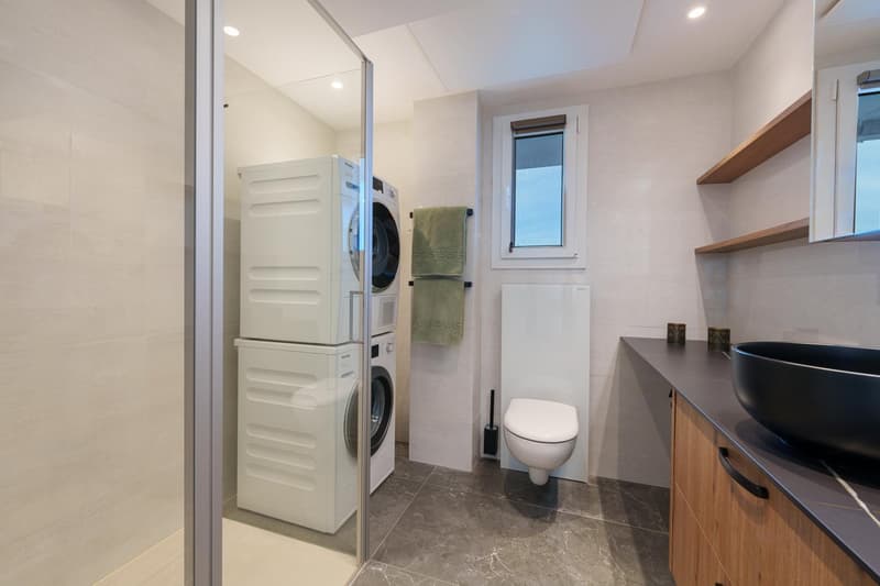 Bathroom with a washer and dryer, toilet, vanity with sink, and shelving