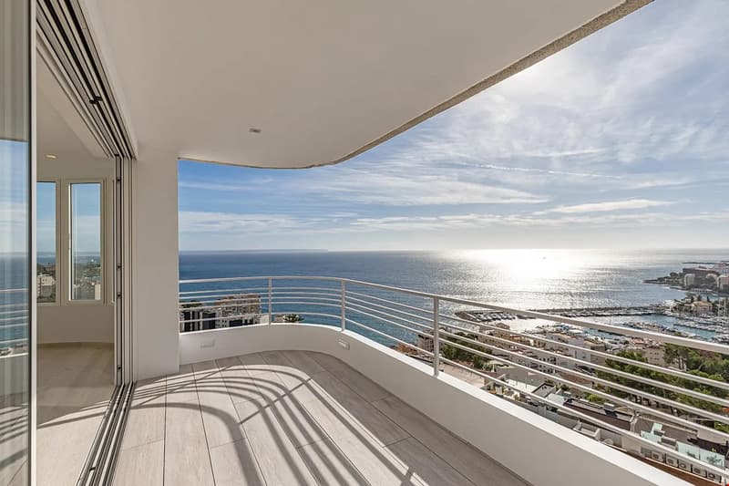 Spacious balcony with panoramic ocean view, sliding glass doors, tiled flooring, and metal railing