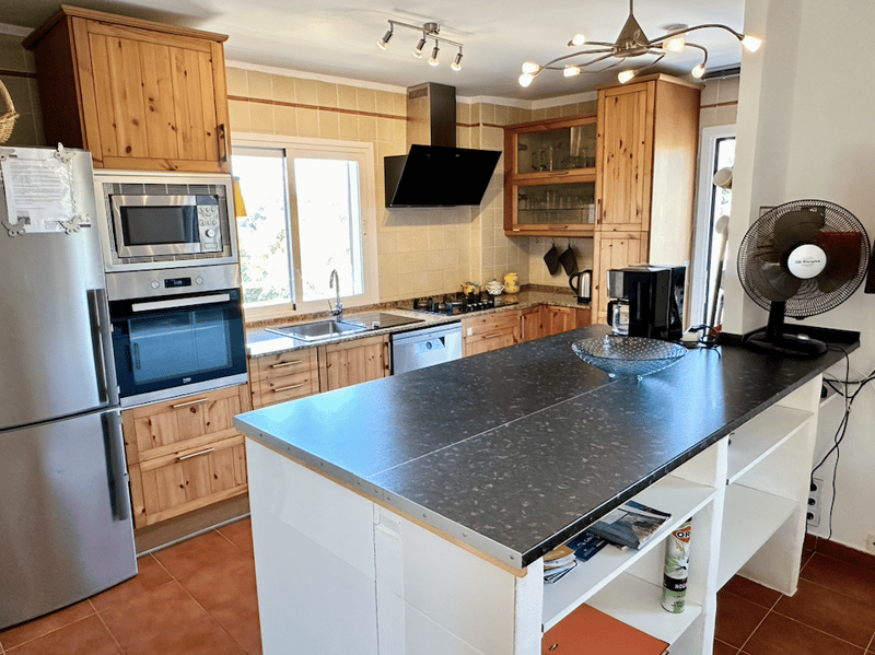 Spacious kitchen with wooden cabinets, stainless steel appliances including oven and microwave, granite countertops, and a central island with additional storage and counter space.