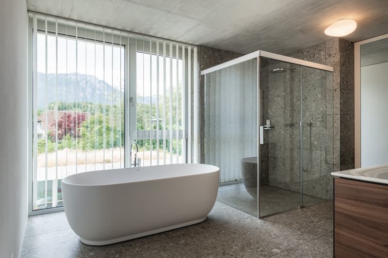 white bathtub, large windows with view, glass shower enclosure, tiled floor