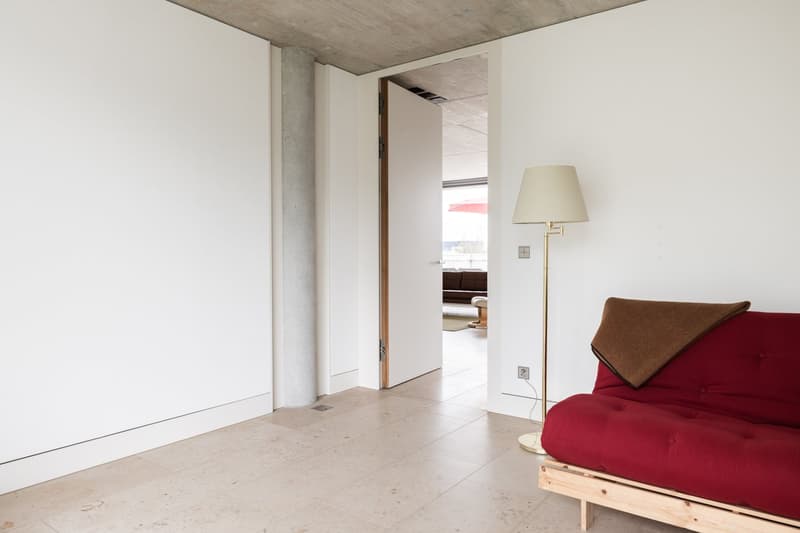 white walls, white tiles, wooden futon couch, lamp