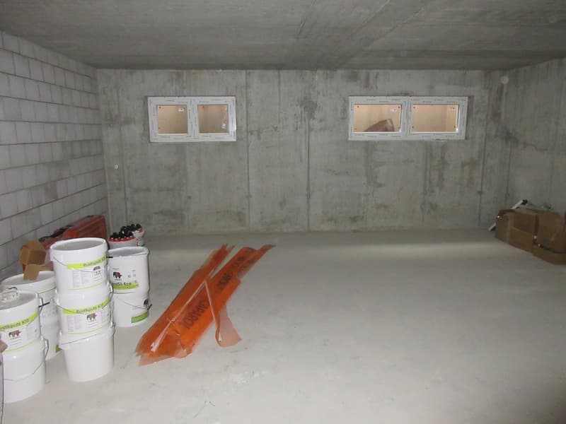 unfinished room, concrete walls, two small windows, buckets, orange strips