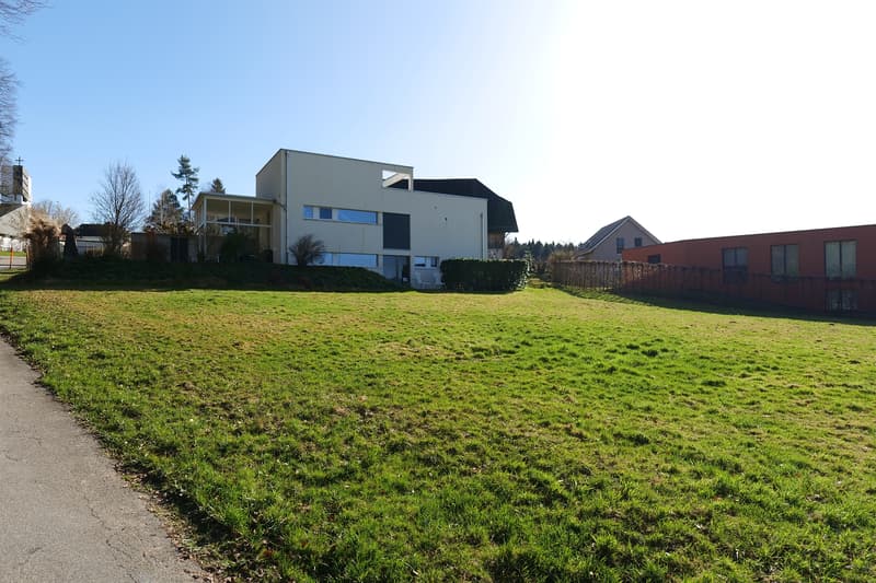 Modern house, white exterior, large windows, glass porch, surrounded by a large green lawn