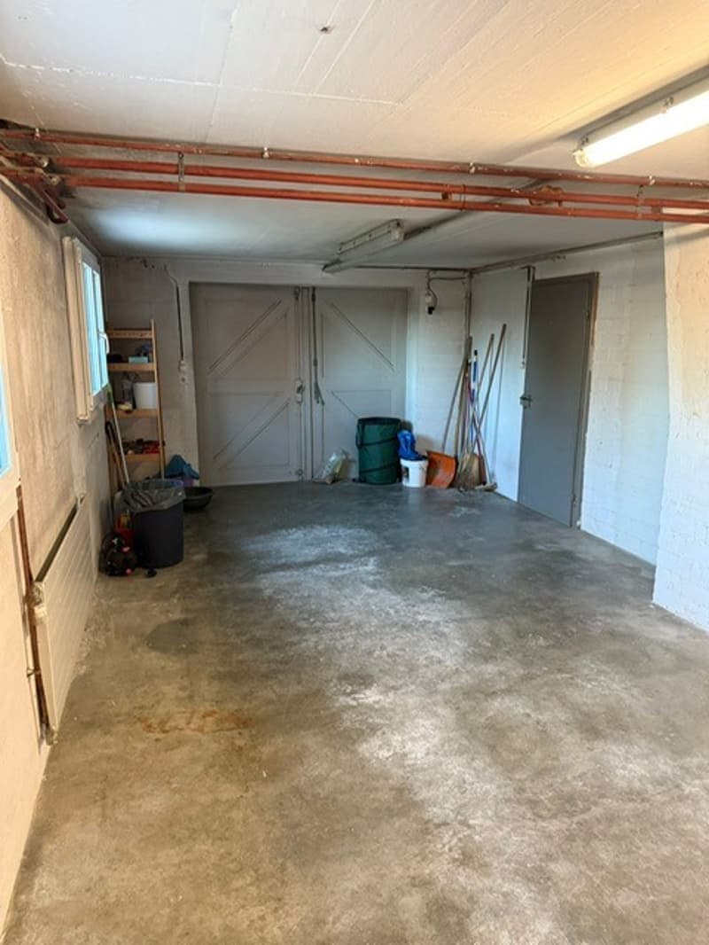 empty room with concrete floor, 2 doors, shelves, buckets, brooms, buckets, radiator