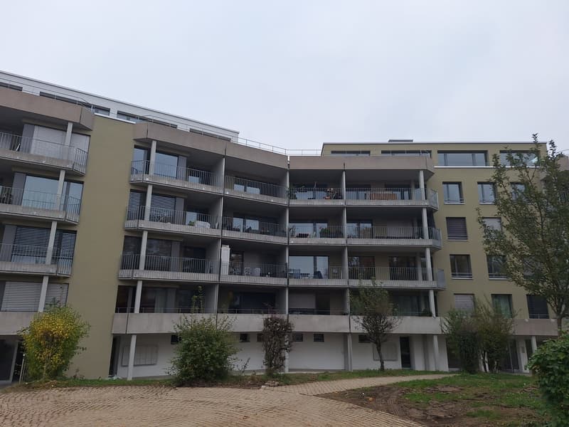 multi-story building, multiple balconies, glass windows, paved entrance