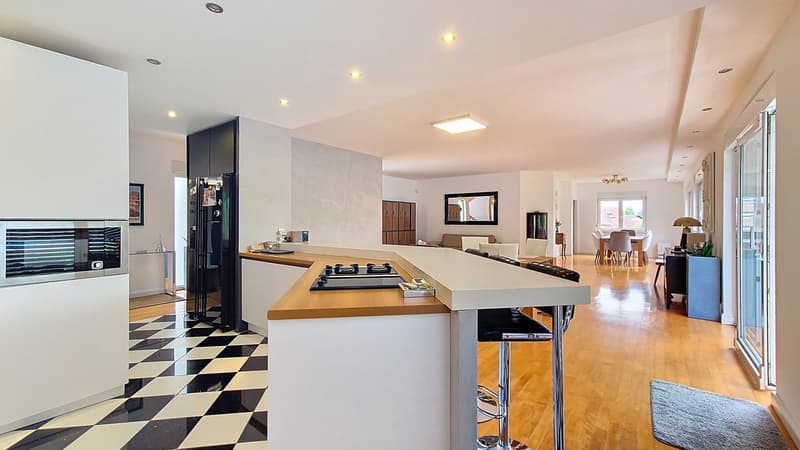 modern kitchen, island with seating, gas stove, integrated oven, black and white checkered floor, large windows