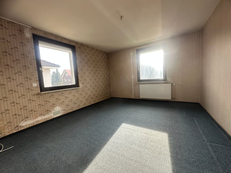 empty room, floral wallpaper, grey floor, two windows, wall-mounted radiator