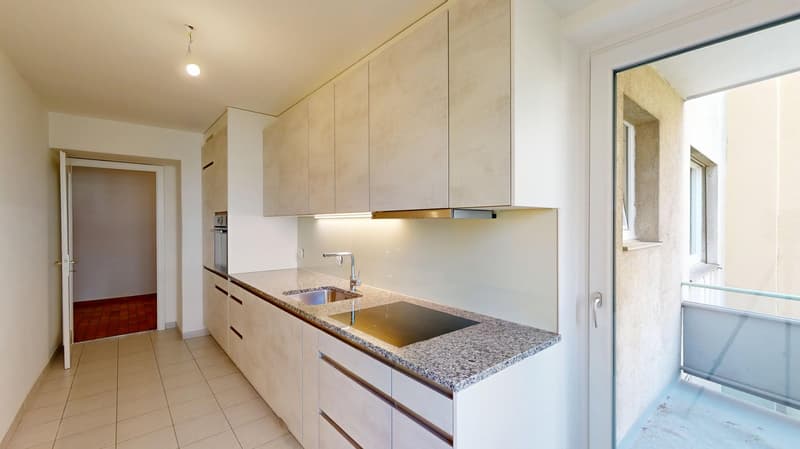 Modern kitchen with granite countertops, modern sink, stainless steel faucet, under cabinet lighting, white cupboards, wooden tile flooring, open to balcony with glass railings.