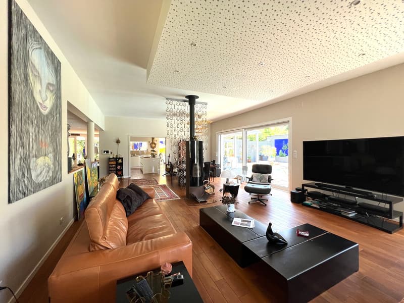 Open plan living room, brown leather couch, wooden floor, fireplace, TV, black coffee tables