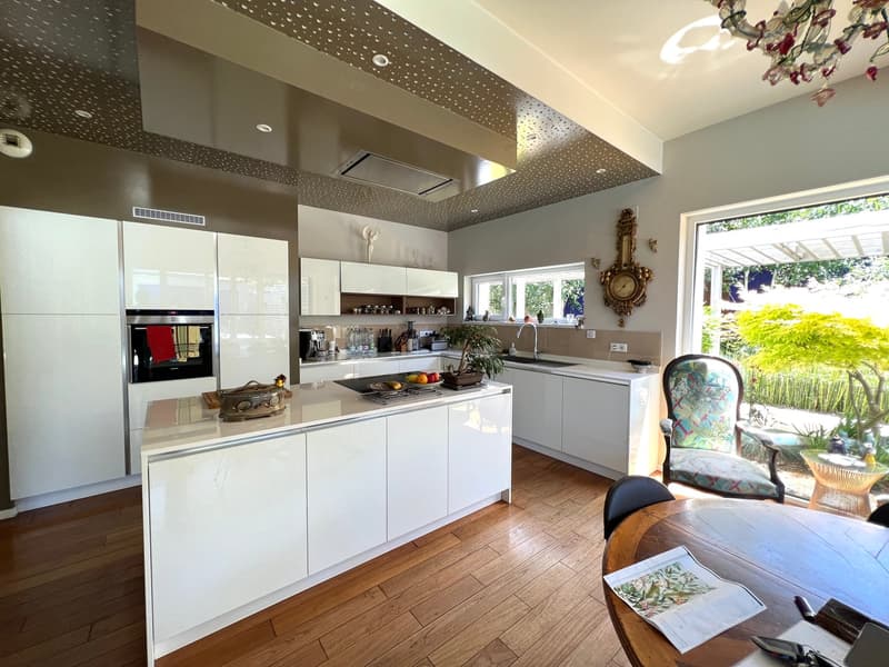 modern kitchen with white cabinets, granite countertop, oven, fridge, island with stove, dining table, chandelier